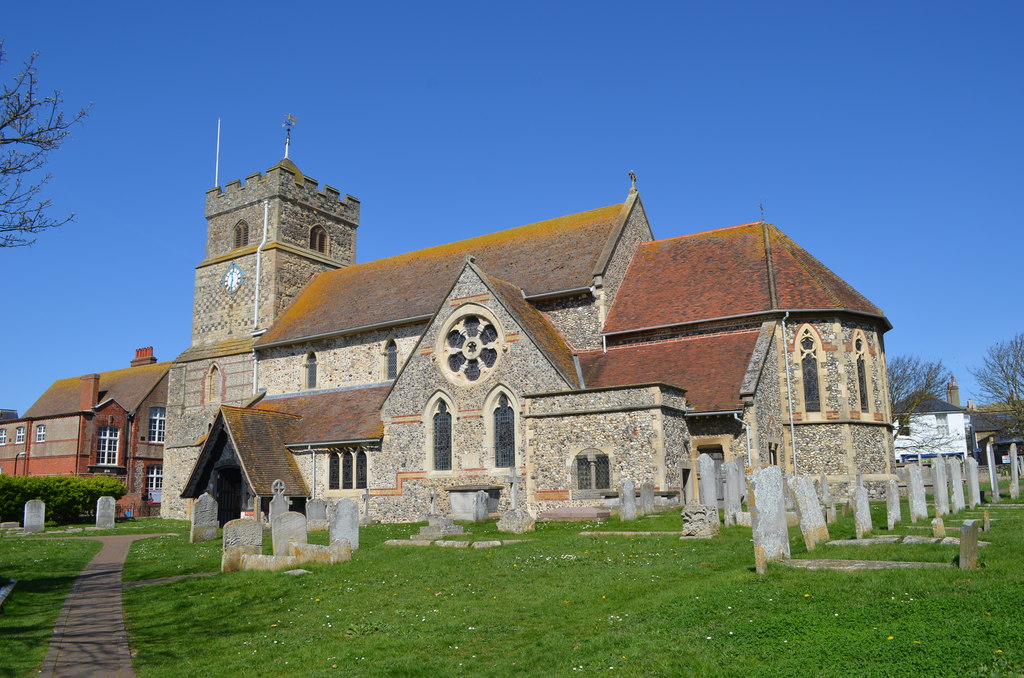 St Leonard's Church, Seaford, a flint church with a square tower, seen across its churchyard